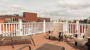 A rooftop deck with outdoor seating and a view of buildings in the background.