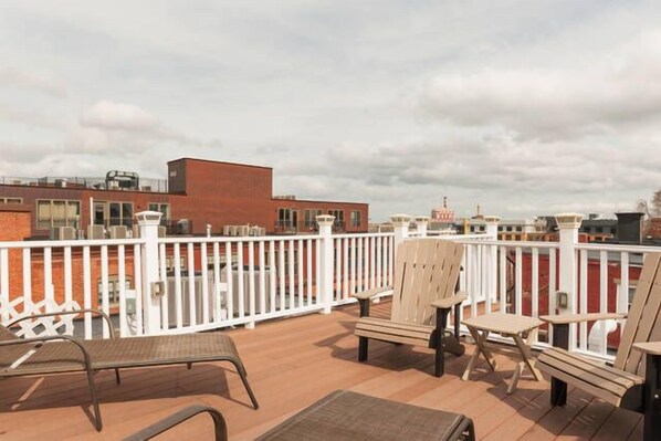 A rooftop deck with outdoor seating and a view of buildings in the background.