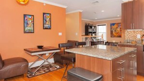 A modern kitchen with a granite countertop, wooden cabinets, and a dining area with a table and chairs.