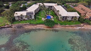 An aerial view of a resort with multiple buildings, a swimming pool, and a beachfront.