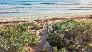 A wooden boardwalk leading to beach chairs overlooking the ocean.