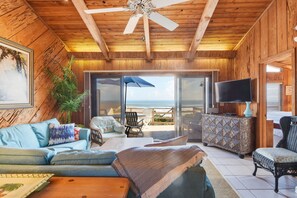 Un interior de madera con un sofá, sillas, un televisor y vistas al exterior.