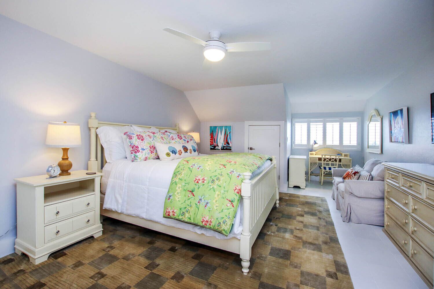 A bedroom with a bed, nightstand, dresser, and a desk with a chair.