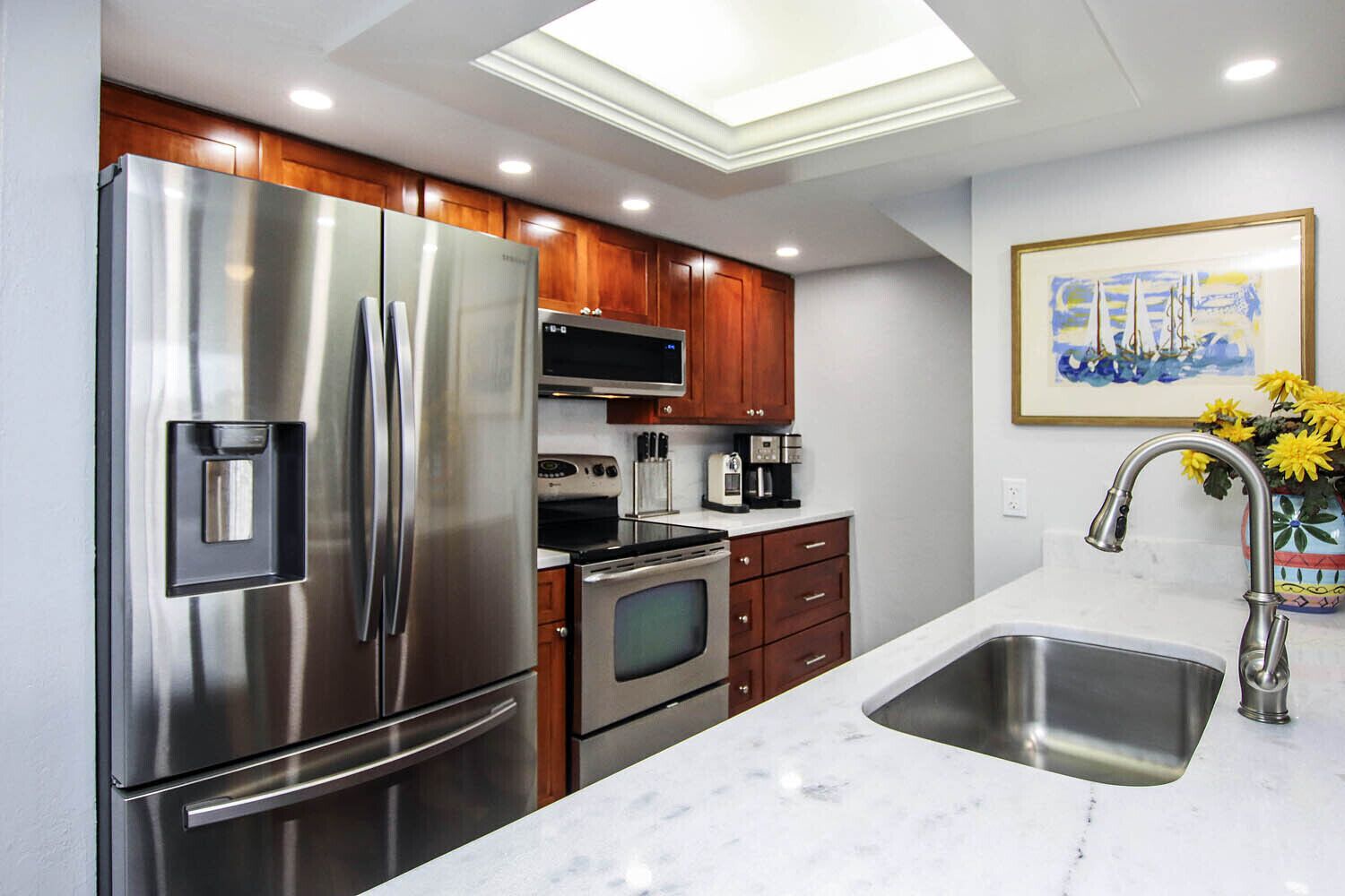 A modern kitchen with stainless steel appliances, wooden cabinets, and a marble countertop.