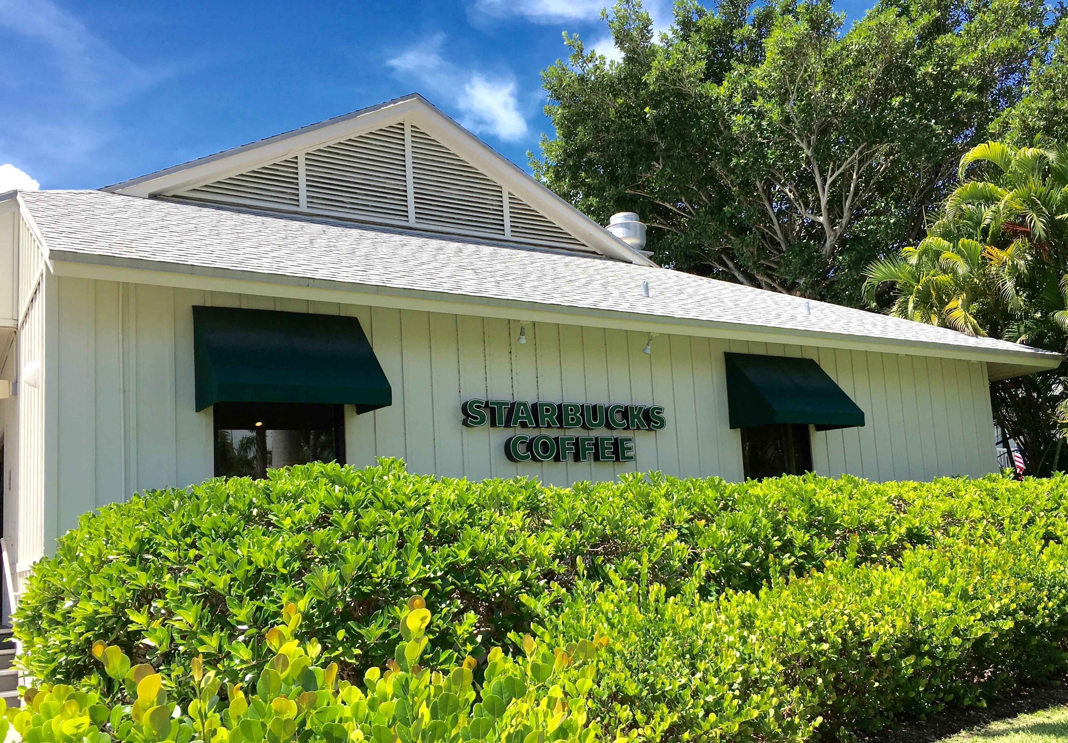 A white building with a green awning and a sign that reads 'Starbucks Coffee'.
