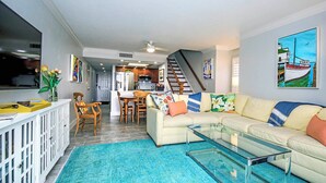 A living room with a sofa, coffee table, and a dining area with chairs and a table.