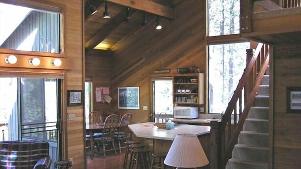 A cozy cabin interior with a dining area, a living room with a sofa, and a staircase. - Your home away from home at Black Butte Ranch! (Sisters)