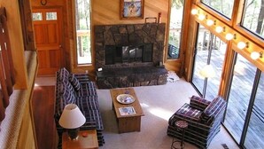 A cozy living room with a stone fireplace, a sofa, a coffee table, and a bench. - Your home away from home at Black Butte Ranch! (Sisters)