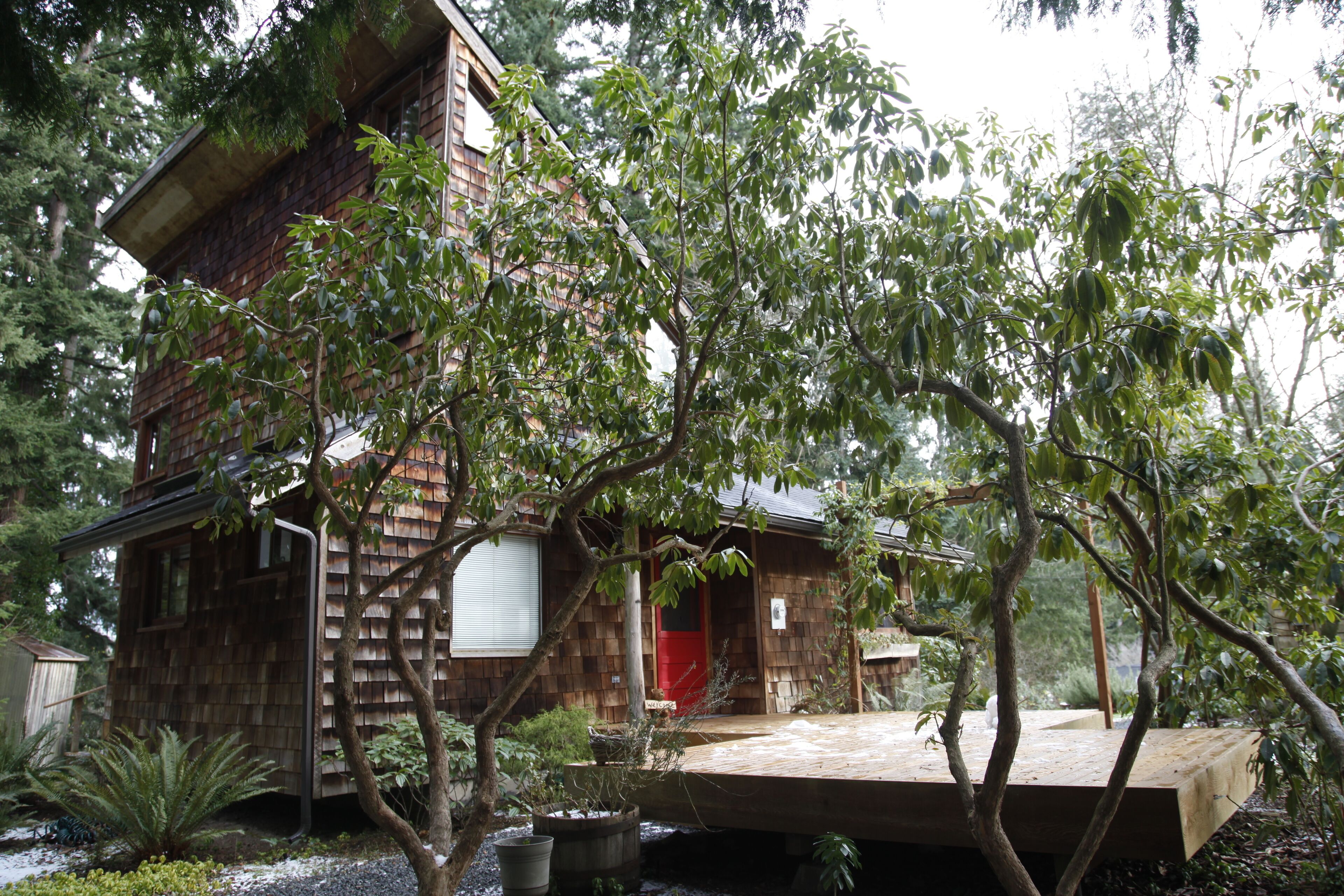 Cabin with large deck nestled in the trees.