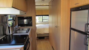A compact RV kitchen with a microwave, stove, and refrigerator. - Unique Retreat - Airstream in Central Location - Remote Feeling. (Tucson)
