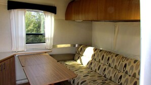 A compact RV interior with a kitchenette, a dining table, and a patterned sofa. - Unique Retreat - Airstream in Central Location - Remote Feeling. (Tucson)