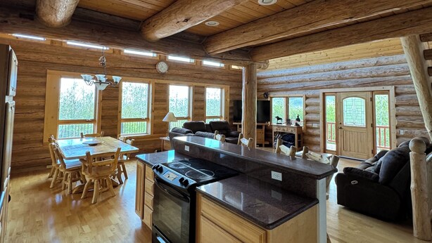 Ein geräumiges Blockhaus-Interieur mit einer großen Küche, einem Essbereich und einem Wohnzimmer.