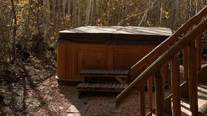 Ein hölzernes Whirlpool inmitten von Bäumen, mit einer Holztreppe, die hinaufführt.