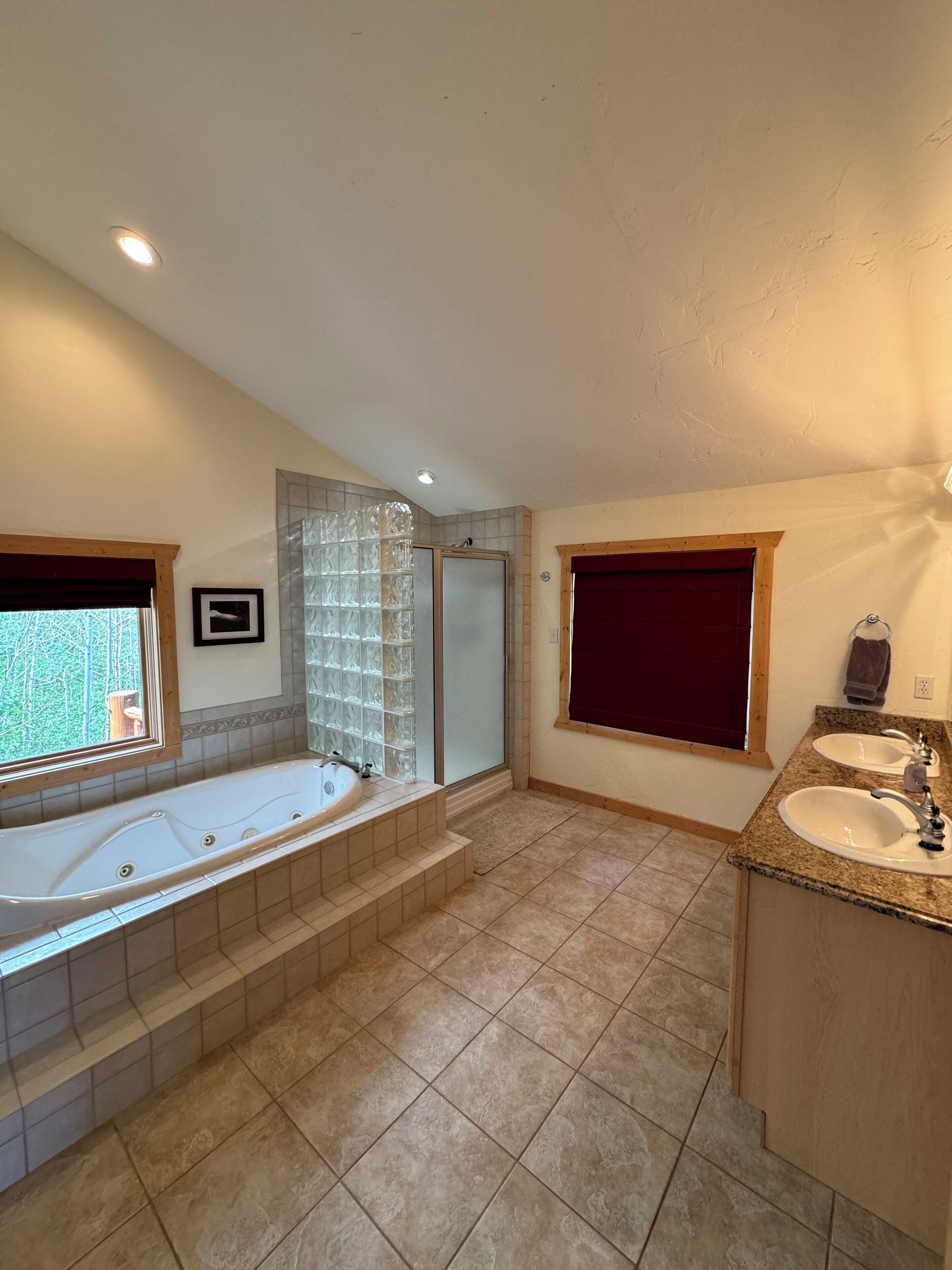 A spacious bathroom with a large bathtub, a separate shower area, and a vanity with two sinks.