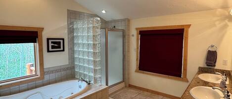 A spacious bathroom with a large bathtub, a separate shower area, and a vanity with two sinks.