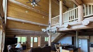 Ein geräumiges Blockhaus-Interieur mit Essbereich, Küche und einem Erkerbalkon.