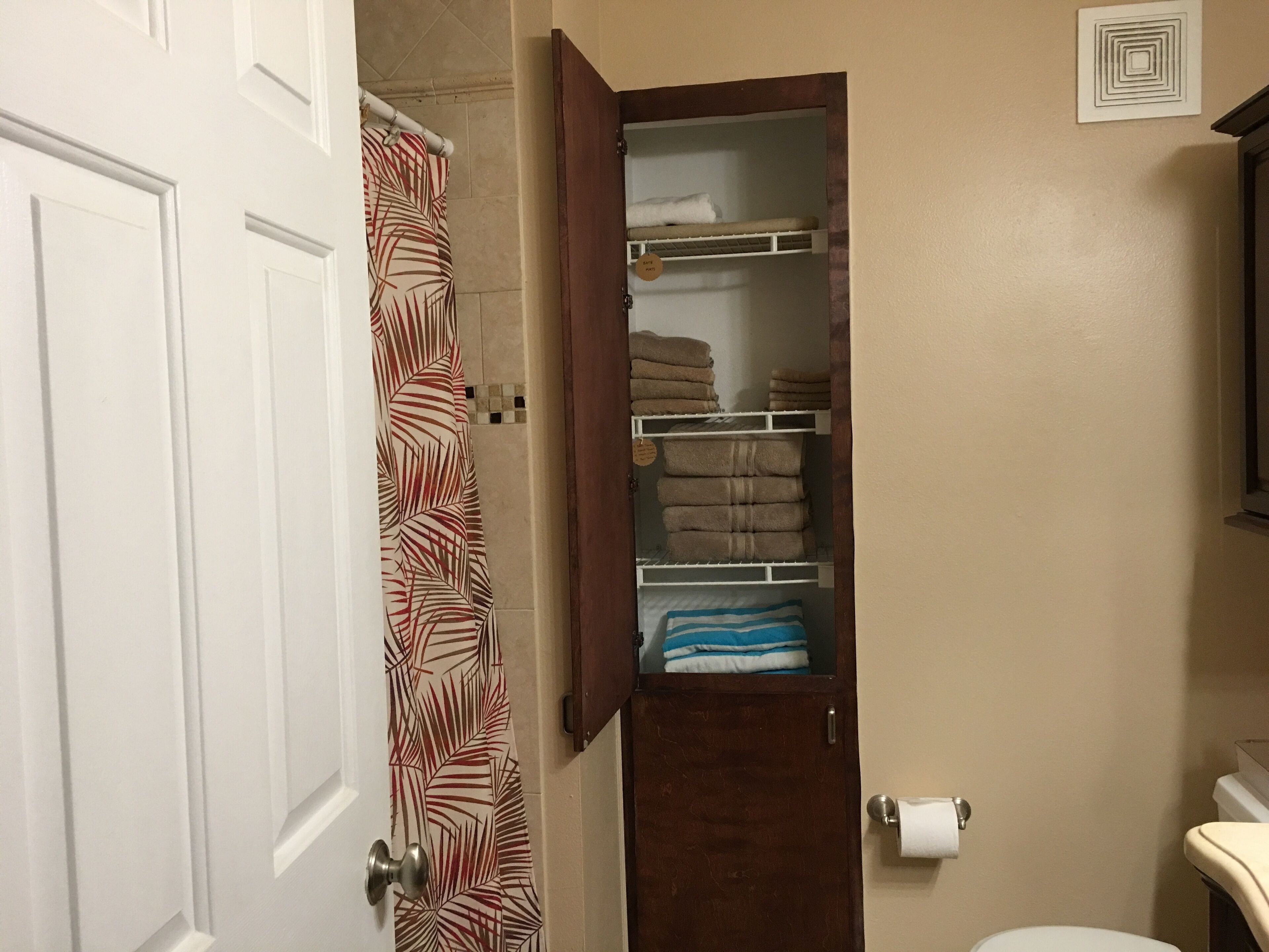 A bathroom with a shower curtain, a towel rack, and a toilet.