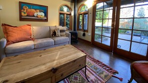 A cozy living room with a sofa, a wooden coffee table, and a painting of pumpkins. - The Napa Art House - w/fireplace & hot tub Near Downtown Napa (Napa)