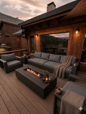 Une terrasse avec un foyer, des canapés et une vue sur les montagnes.