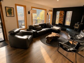 Un salon moderne avec un canapé d’angle, une table basse en bois et une cheminée.