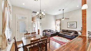 A dining area with a wooden table and chairs, a black leather sofa, and a chandelier. - 4 bedroom with Swimming Pool,  NEAR FRENCH QUARTER- (Arabi)