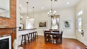 A spacious dining area with a wooden table and chairs, a brick fireplace, and a chandelier. - 4 bedroom with Swimming Pool,  NEAR FRENCH QUARTER- (Arabi)