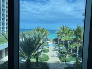 Uitzicht op een resort met een zwembad, palmbomen en een helderblauwe lucht.