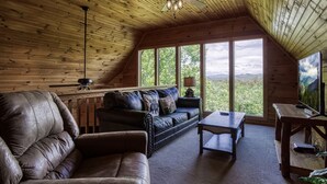 A cozy cabin with a wooden interior, a leather sofa, a coffee table, and a TV on a wooden table. - Mountain and Ferris Wheel View,wifi and Close to Pigeon Forge (SEVIERVILLE)