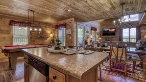 A wooden cabin interior with a pool table, a dining area, and a living room with a television. - Mountain and Ferris Wheel View,wifi and Close to Pigeon Forge (SEVIERVILLE)