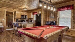 A wooden cabin interior with a pool table, kitchen area, and a cozy seating space. - Mountain and Ferris Wheel View,wifi and Close to Pigeon Forge (SEVIERVILLE)
