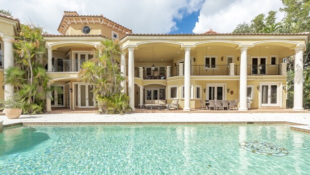 Una casa grande de dos pisos con piscina delantera.