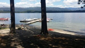 A lakeside view with boats docked, a dock extending into the water, and mountains in the background. - Huckleberry Hideaway: Authentic Cabin Adventure, steps away from Payette Lake (McCall)