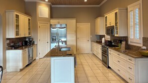A spacious kitchen with a central island, white cabinetry, stainless steel appliances, and a wooden ceiling. - Luxurious 'Old Fort Bay' Large SINGLE LEVEL with 4 bedrooms each with an ensuite (Old Fort Bay)