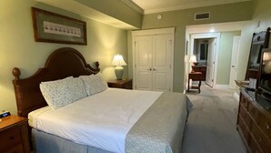 A bedroom with a bed, nightstands, a dresser, a ceiling fan, and a door leading to another room. - Bay views & sunsets in the Grand Sandestin! Baytowne Wharf Village (Destin)
