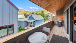 Un balcone con vista su una casa blu, un barbecue e una sedia.
