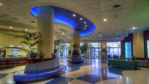 Eine großzügige Lobby mit Check-in-Schalter, Sitzbereichen und hohen Säulen.