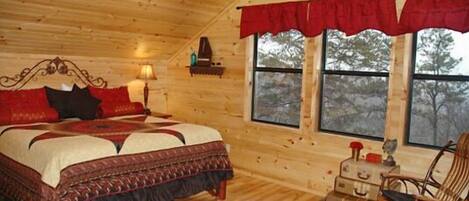 Un dormitorio de cabaña de madera acogedor, con una cama, una mesita de noche, una lámpara, una ventana con cortinas y una decoración de estrella en la pared.