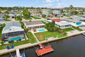 A residential area with houses, a swimming pool, and a dock with a boat.