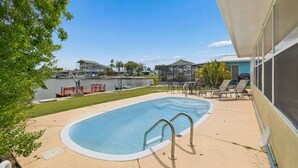 Une piscine dotée d’une terrasse, de chaises longues et d’un espace patio couvert.