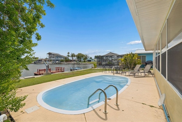 A swimming pool with a deck, lounge chairs, and a covered patio area.