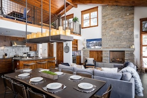 Enjoy a comfortable living space with a stone fireplace, dining area for six, and a balcony with potted plants.