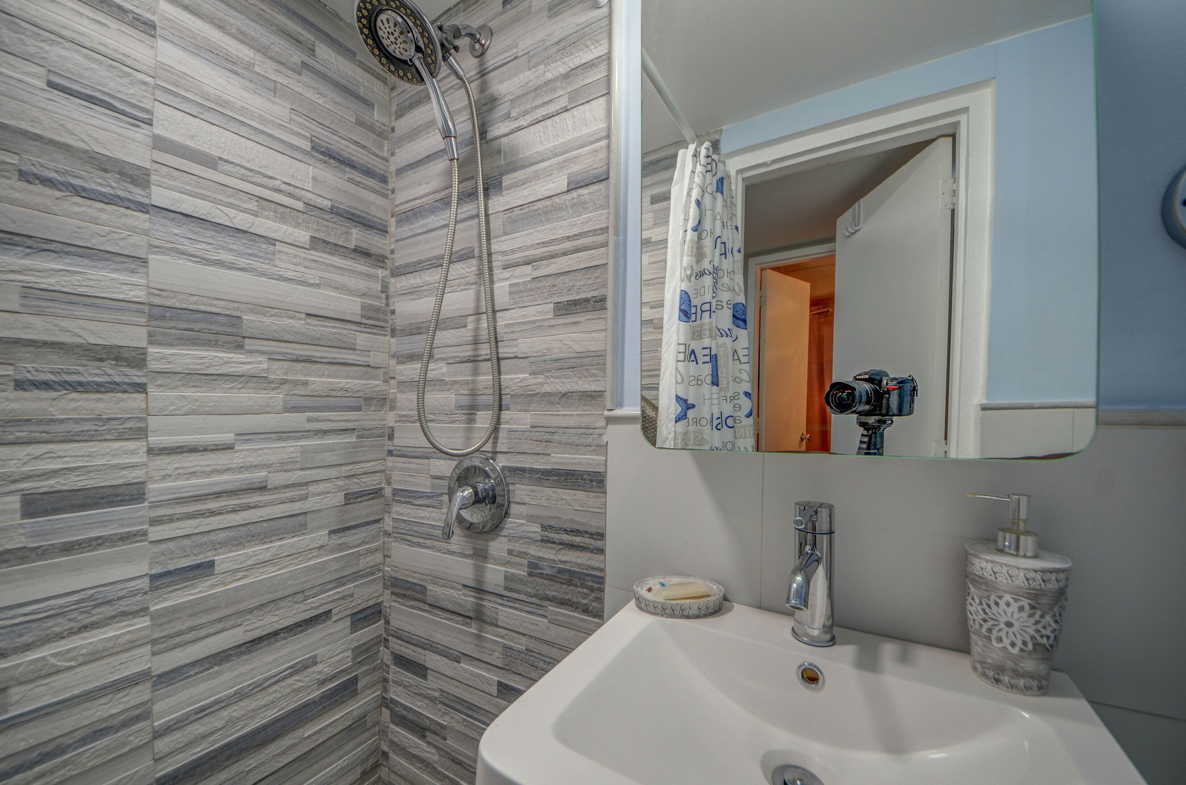 Un baño con ducha, lavabo y espejo.