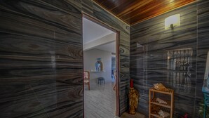 A room with dark marble walls, a wooden ceiling, and a small wooden shelf with decorative items.