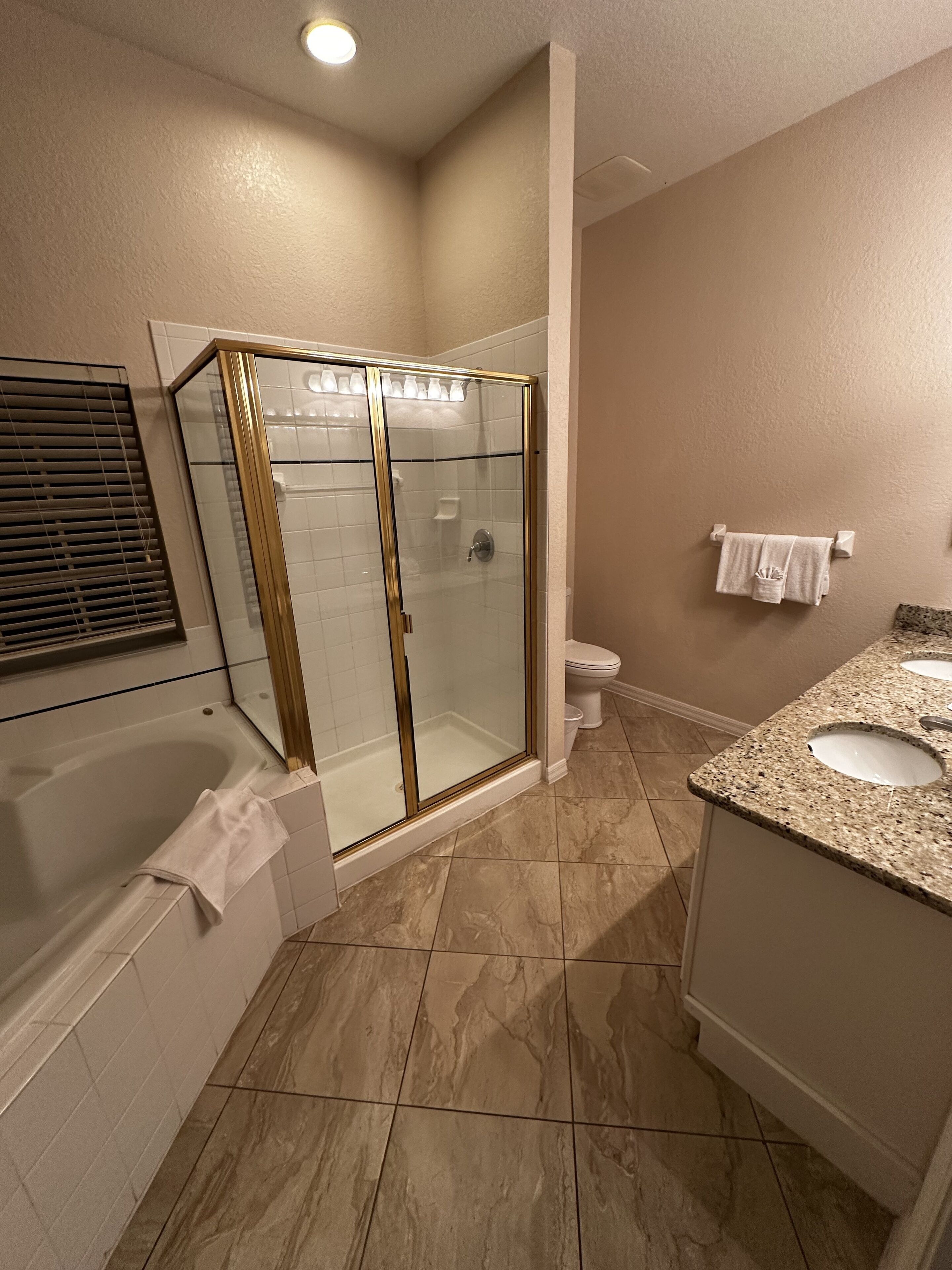 Et badeværelse med bruseniche, badekar og et toiletbord med to vaske.