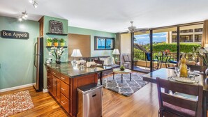 A modern kitchen with a large island, wooden cabinets, and a view of the outdoor patio. - SUGAR BEACH RESORT 10% DSCNT on 7 days Stay - Renovated Condo 201 (Kihei)