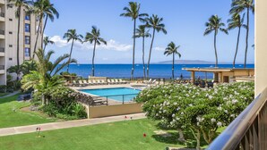 A pool area with lounge chairs, palm trees, and a view of the ocean. - SUGAR BEACH RESORT 10% DSCNT on 7 days Stay - Renovated Condo 201 (Kihei)