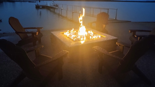 Un foyer avec des chaises disposées autour, donnant sur une étendue d’eau calme.
