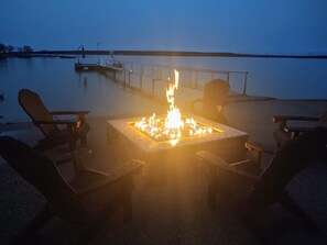A fire pit with chairs around it, overlooking a calm body of water. - The Cottage on Lake Graham (Graham)
