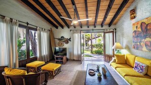 A cozy living room with a wooden ceiling, a television, a sofa, and a dining table. - Casa Colibri - Los Delfines (Sayulita)