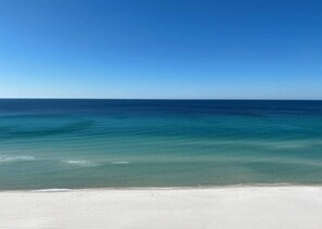 Une plage à l’eau d’un bleu limpide et au sable blanc.